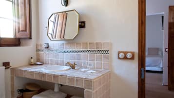 Une salle de bain avec un lavabo carrelé, un miroir et un porte-serviettes.