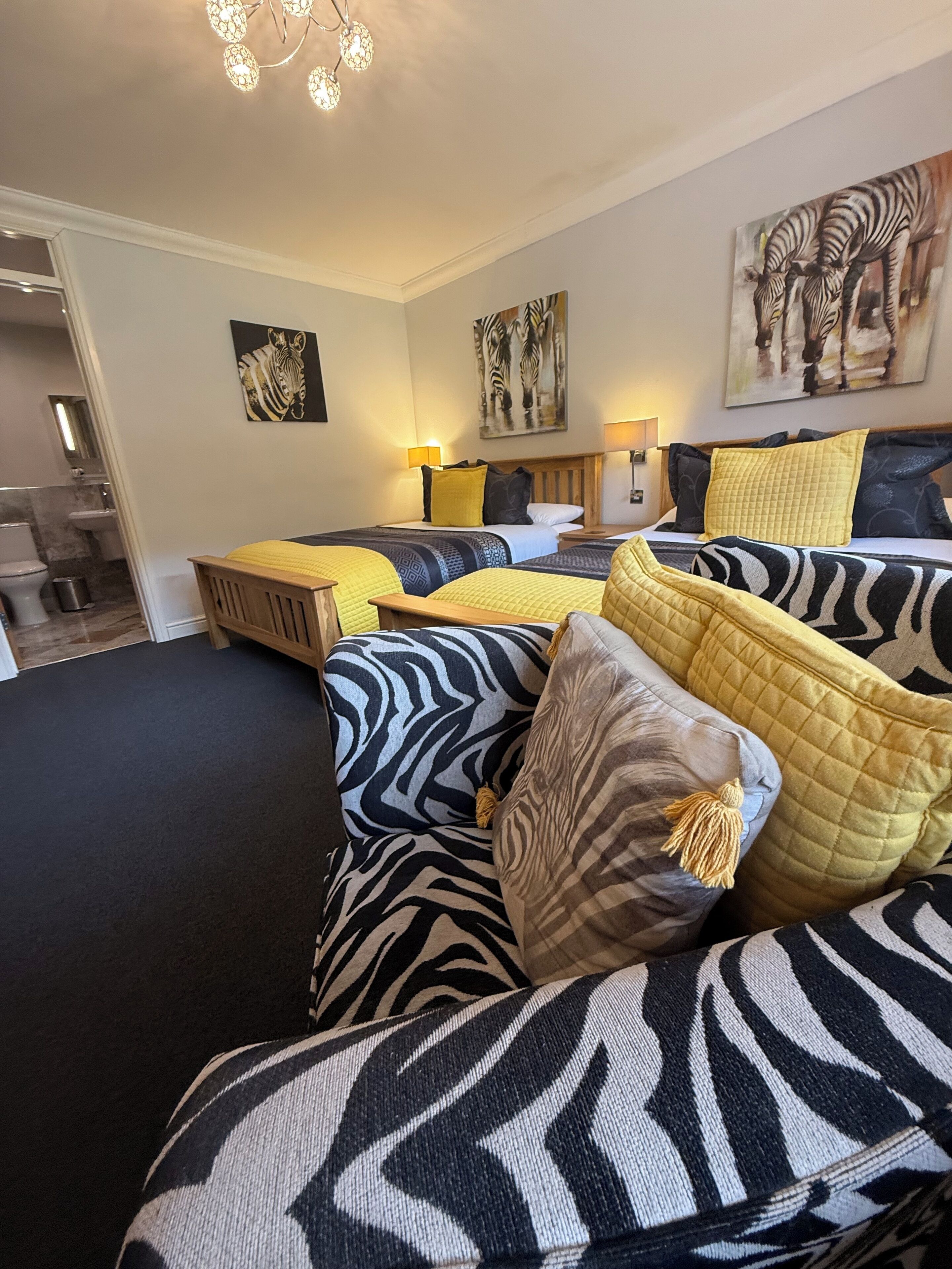 A bedroom with a zebra-themed bedspread, multiple pillows, and artwork on the walls.
