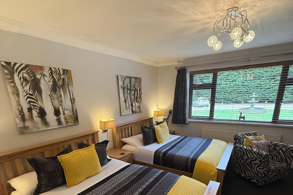 Een hotelkamer met twee bedden, een groot raam met uitzicht op groen en zwart-wit gestreepte kunst aan de muren.