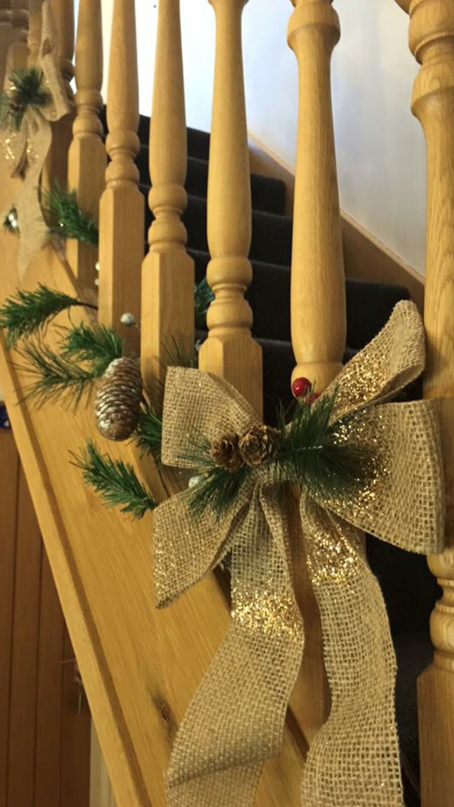 A wooden staircase with a decorative bow and pine decorations.