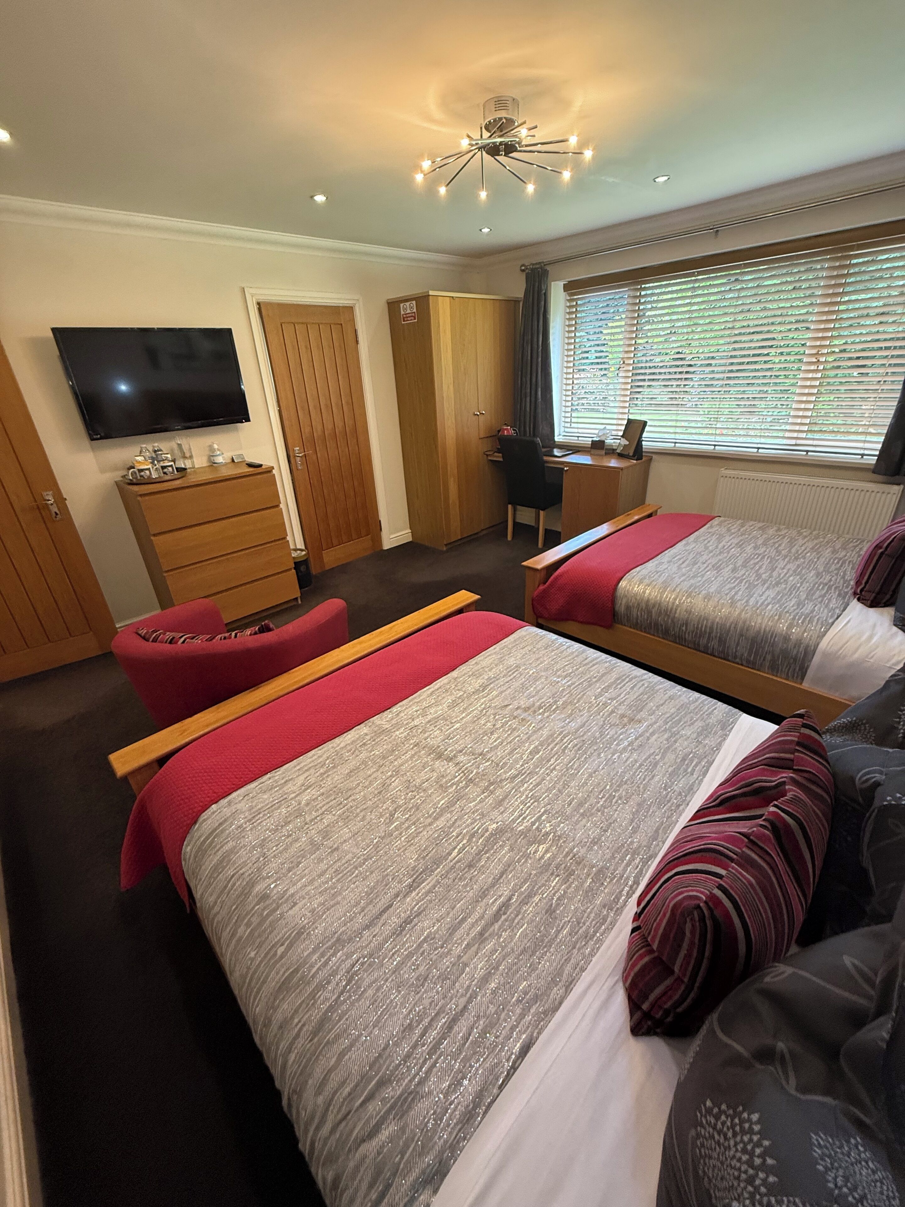 A hotel room with two beds, a desk, a chair, a TV, and a wardrobe.