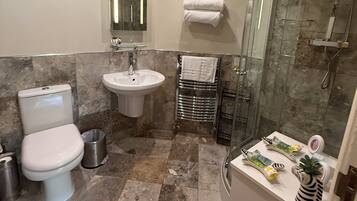 A bathroom with a toilet, sink, and shower.