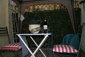Una piccola zona con posti a sedere all'aperto, un tavolo, sedie e una ciotola decorativa.