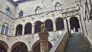 Edificio de piedra con una escalera central, arcos y una columna en primer plano.