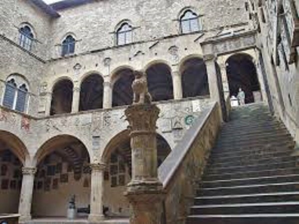 A stone building with a central staircase, arched doorways, and a column in the foreground. - La corte di Firenze (Florence)