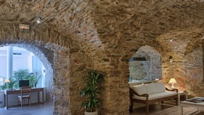 A room with stone walls, a wooden desk, a sofa, and a potted plant. - Hotel el Petit Convent (Begur)