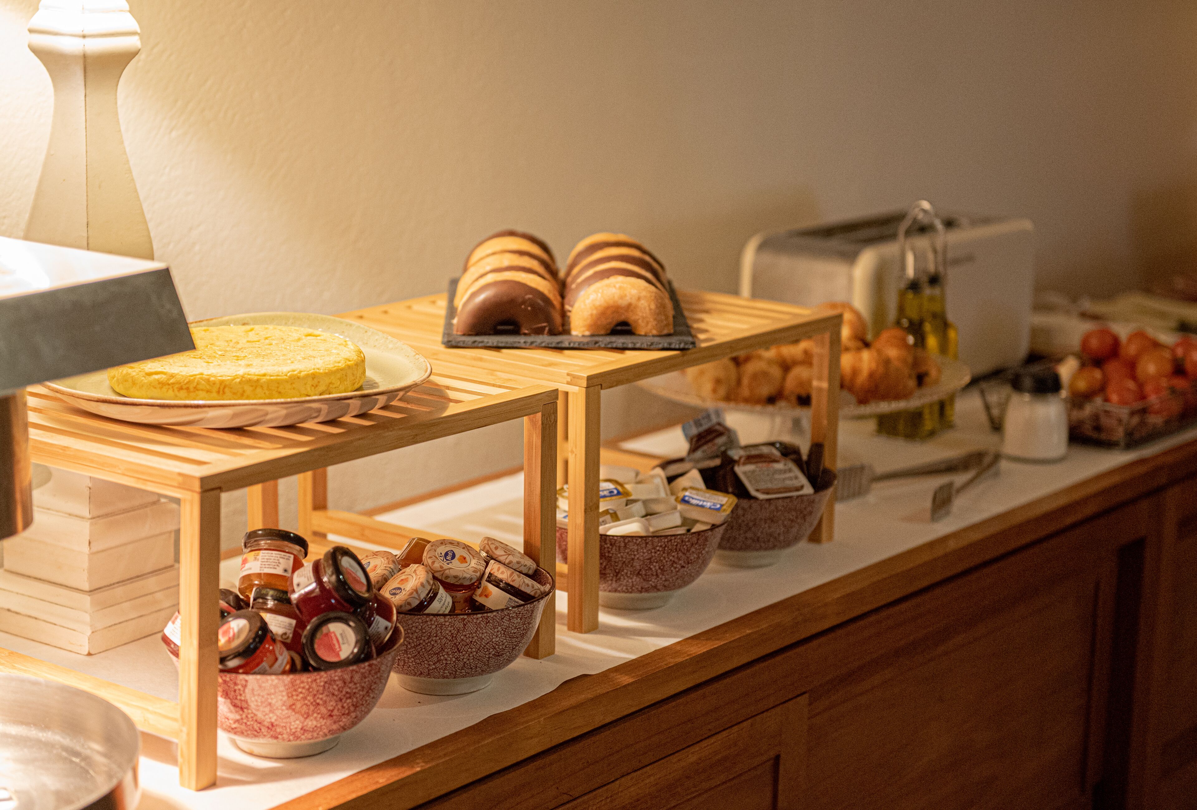 A breakfast buffet with various pastries, bread, and condiments.