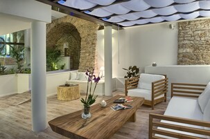 Una sala de estar moderna con una mesa de centro de madera, un sofá blanco y una pared de piedra.
