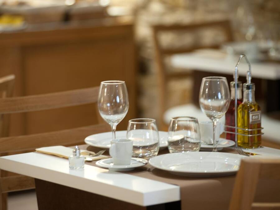 Una mesa de comedor dispuesta con copas de vino, vasos de agua y una botella de vino.