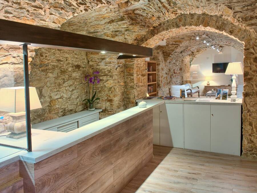 Una recepción con paredes de piedra, un mostrador de madera, una estantería y un televisor montado en la pared.