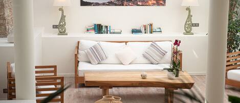 A cozy living room with a wooden sofa, a coffee table, and a bookshelf with books.