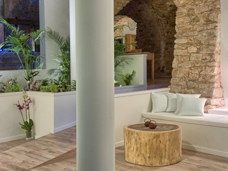 Un interior moderno con una pared de piedra, un sofá blanco y una mesa redonda de madera.