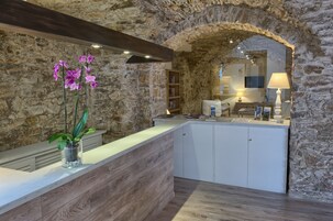 Una cocina con pared de piedra, encimera de madera y una orquídea en maceta.