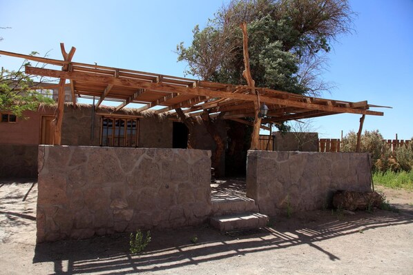 A rustic building with a wooden pergola, stone walls, and a thatched roof. - Sol del Desierto (Calama)
