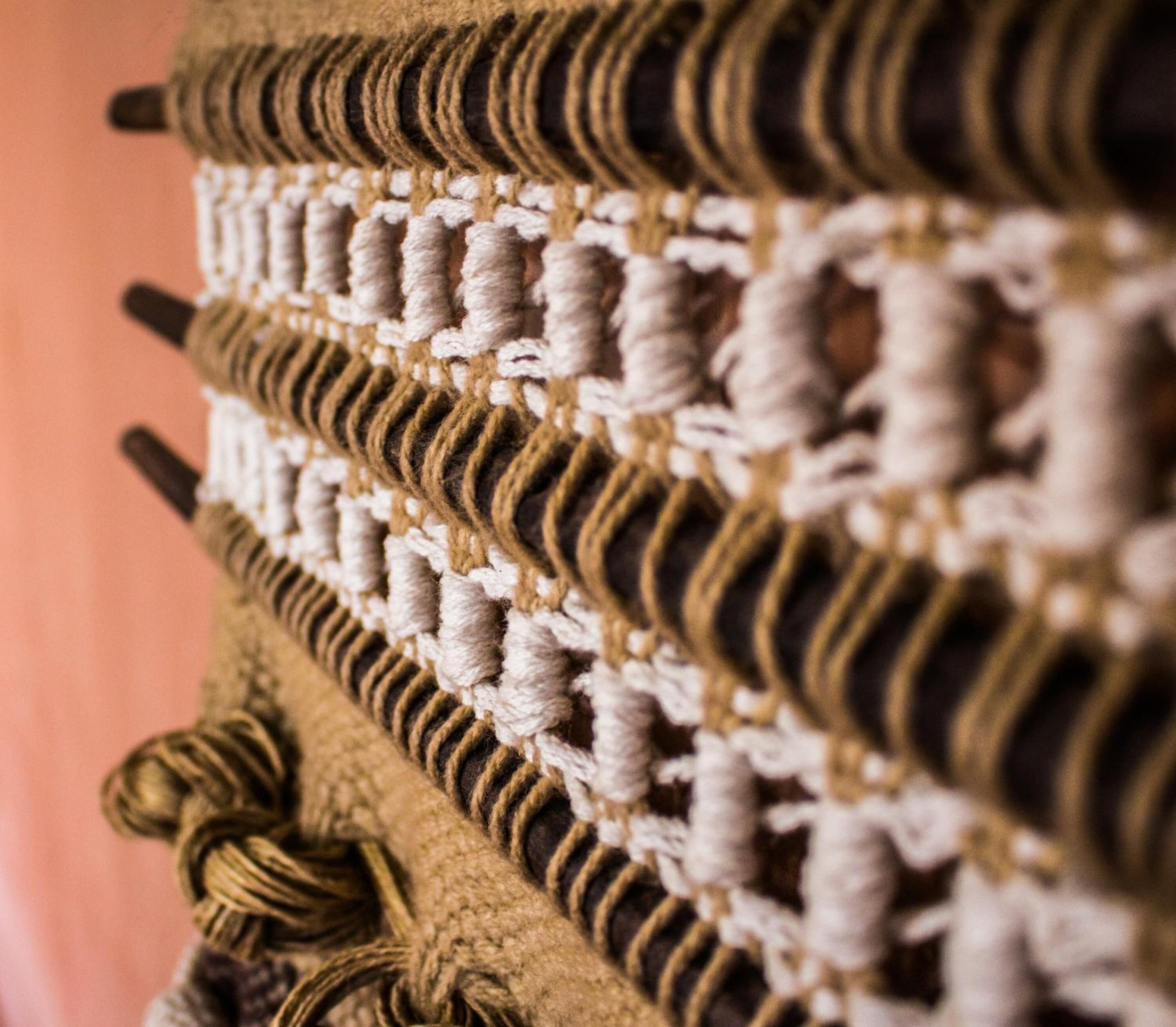 A close-up of a textured wall with a pattern of interwoven ropes and a rope tied in a knot.