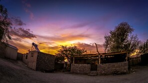 A rural setting with a stone wall, a wooden structure, and a metal telescope.