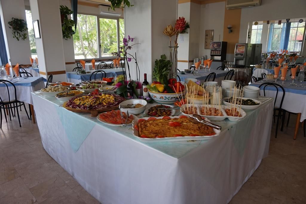 A buffet setup with various dishes and drinks, arranged on tables with chairs around.