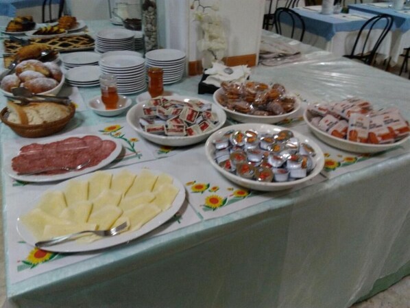Una mesa de buffet con diversos alimentos, incluyendo pan, pasteles y mariscos.