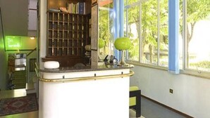 A kitchen with a central island, a bookshelf, and a window with a view of trees. - Hotel Caravan (Pesaro)