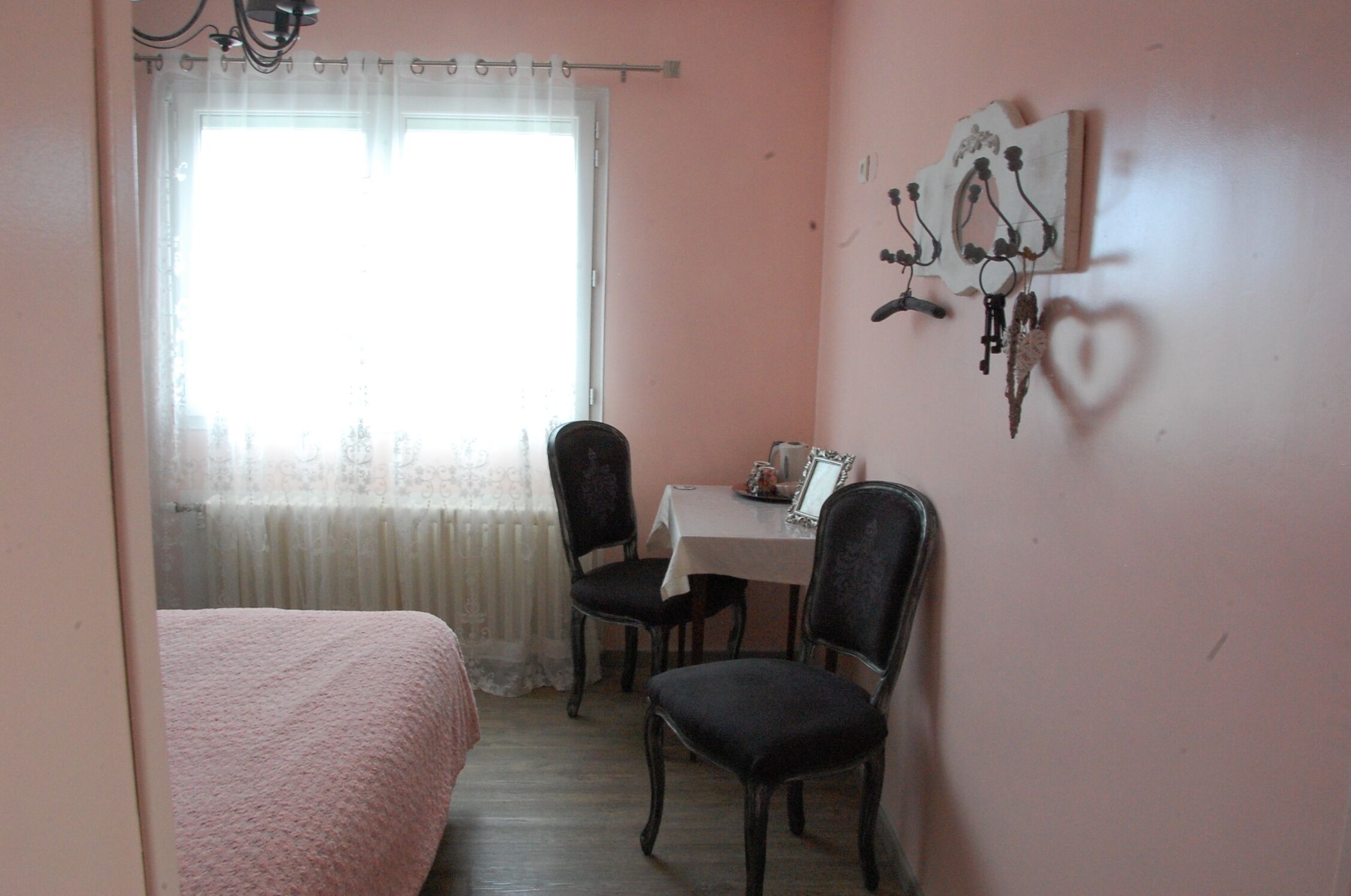 A small room with a bed, a table with chairs, and a window with curtains.