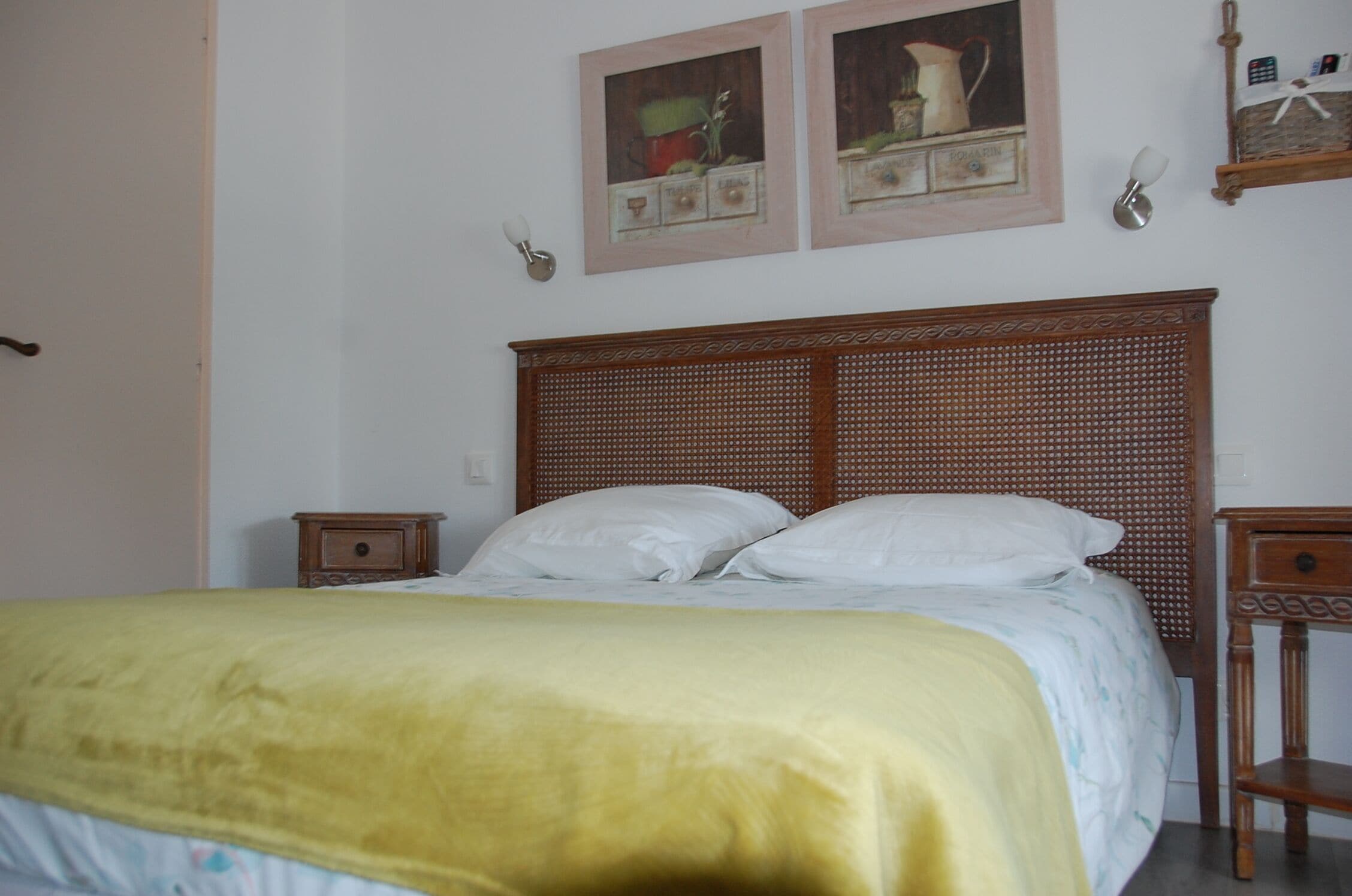 Ein Bett mit hölzernem Kopfteil, zwei Nachttische und eine gelbe Decke.
