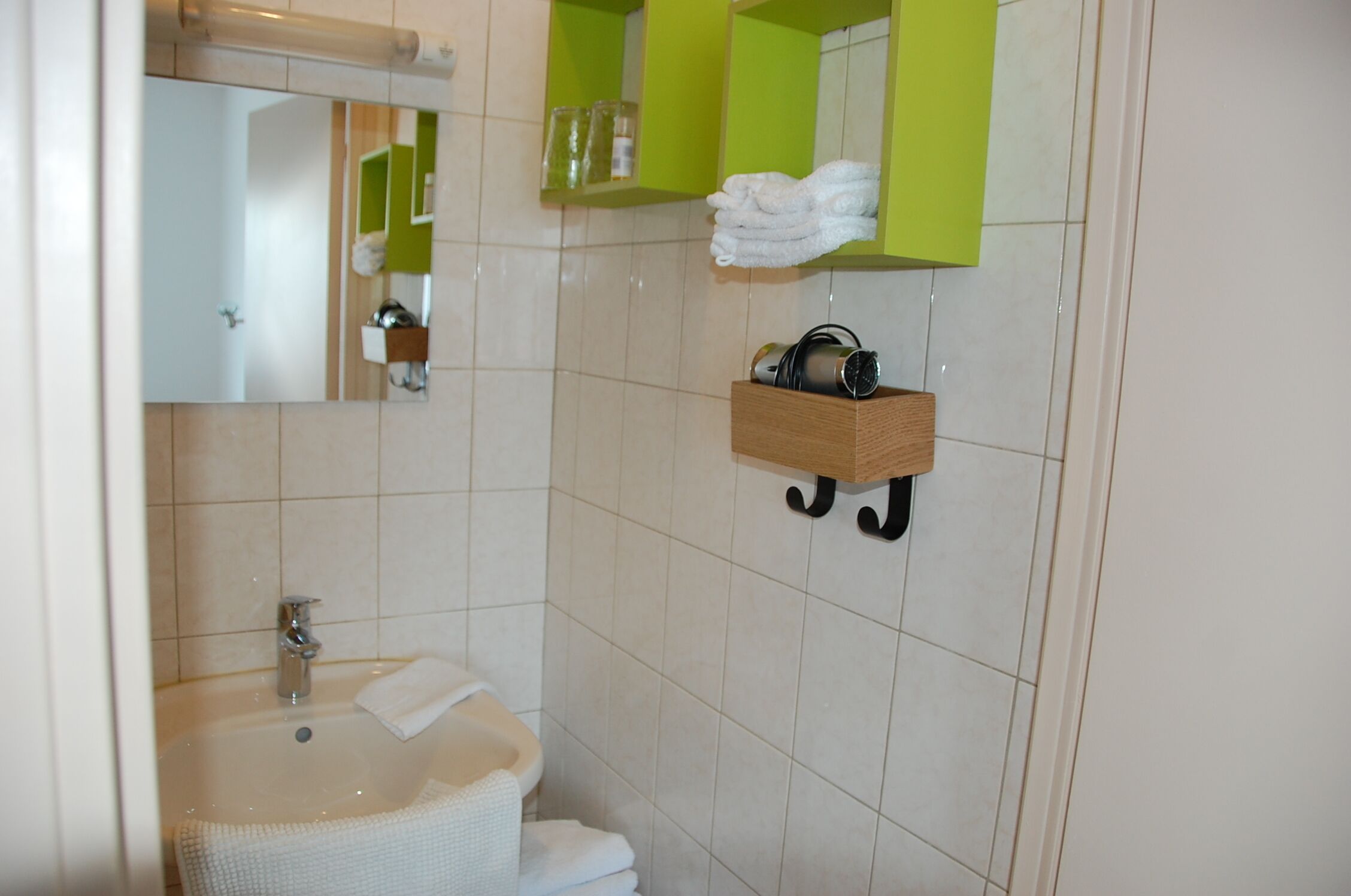 Een badkamer met een wastafel, spiegel en handdoekhouder.