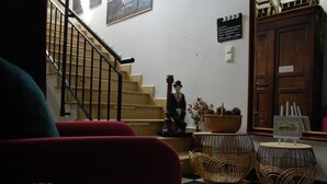 A lobby with a staircase, a statue, wicker furniture, and a framed picture on a small table. - Le Pont de la Loire (Bourbon-Lancy)
