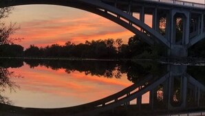 A bridge with a clear reflection in the water, surrounded by trees and a sunset sky. - Le Pont de la Loire (Bourbon-Lancy)