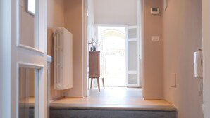 Una escalera conduce a una habitación luminosa con un radiador, un teléfono y vistas al exterior.