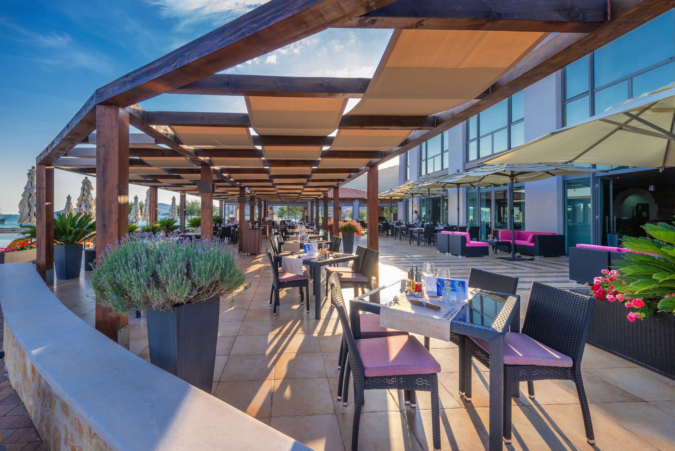 An outdoor patio area with wooden pergolas, tables, chairs, and potted plants.