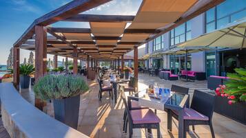 An outdoor patio area with wooden pergolas, tables, chairs, and potted plants.