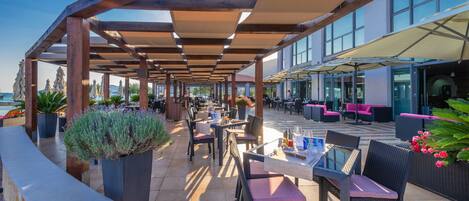 An outdoor patio area with wooden pergolas, tables, chairs, and potted plants.