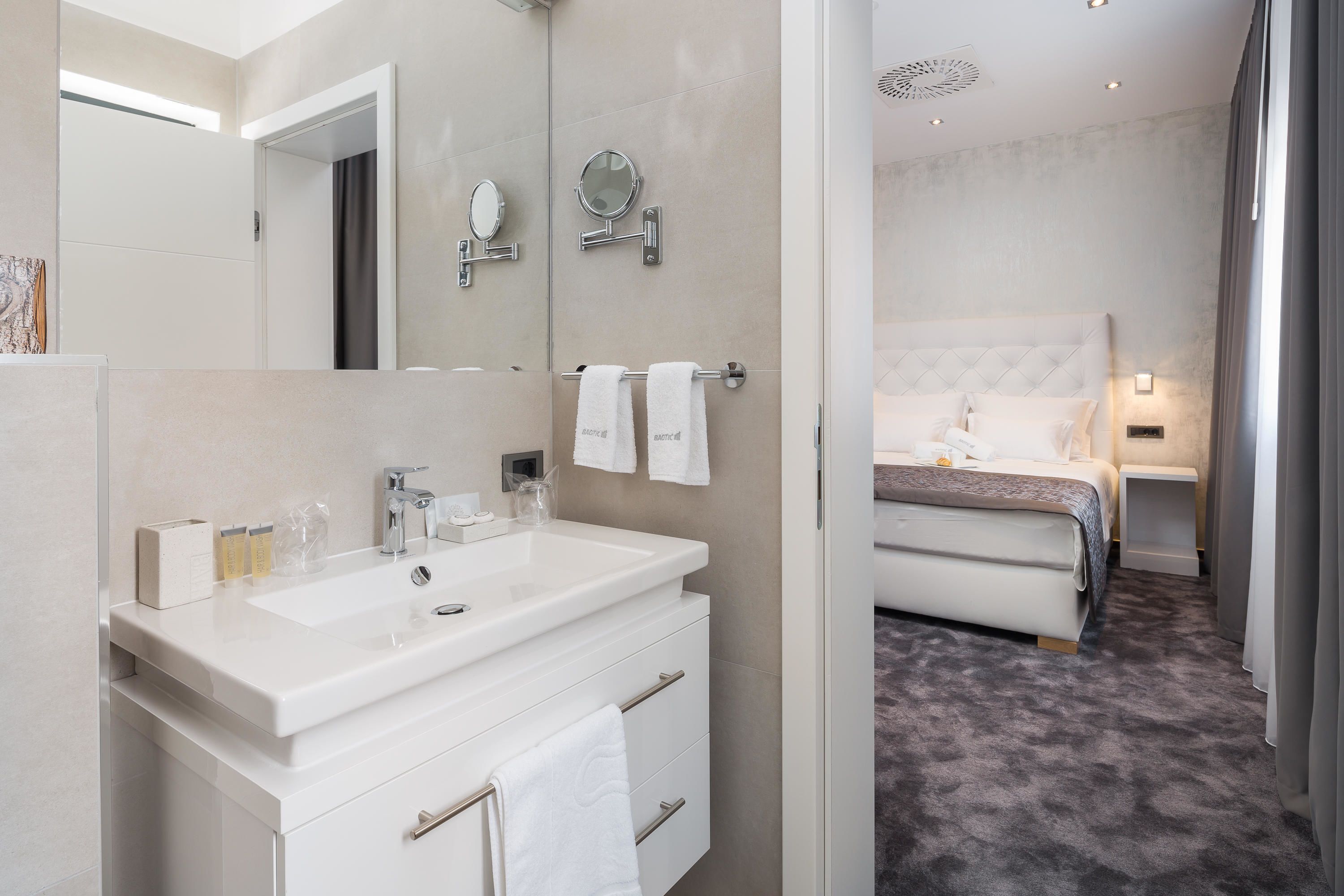 Een moderne badkamer met een grote spiegel, een witte wastafel en een badkamermeubel.