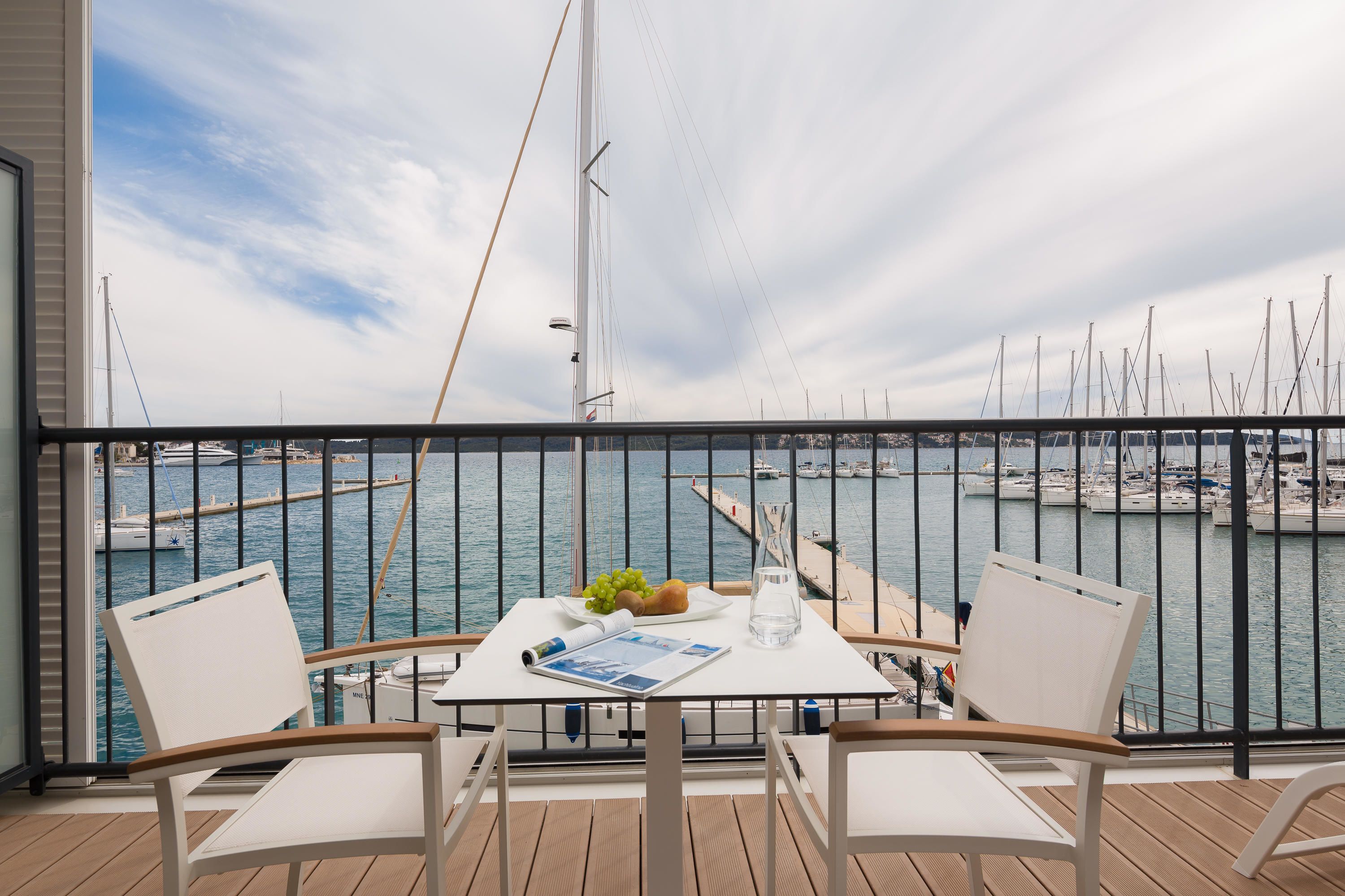A balcony with a table, two chairs, and a view of the marina.