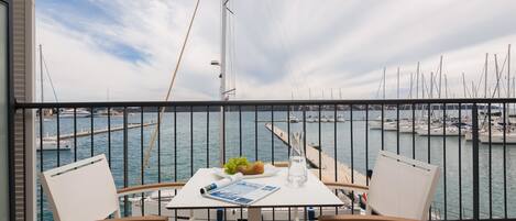 A balcony with a table, two chairs, and a view of the marina.