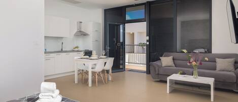 Una sala de estar moderna con un sofá gris, una mesa de centro con un florero, y un comedor con una mesa y sillas.
