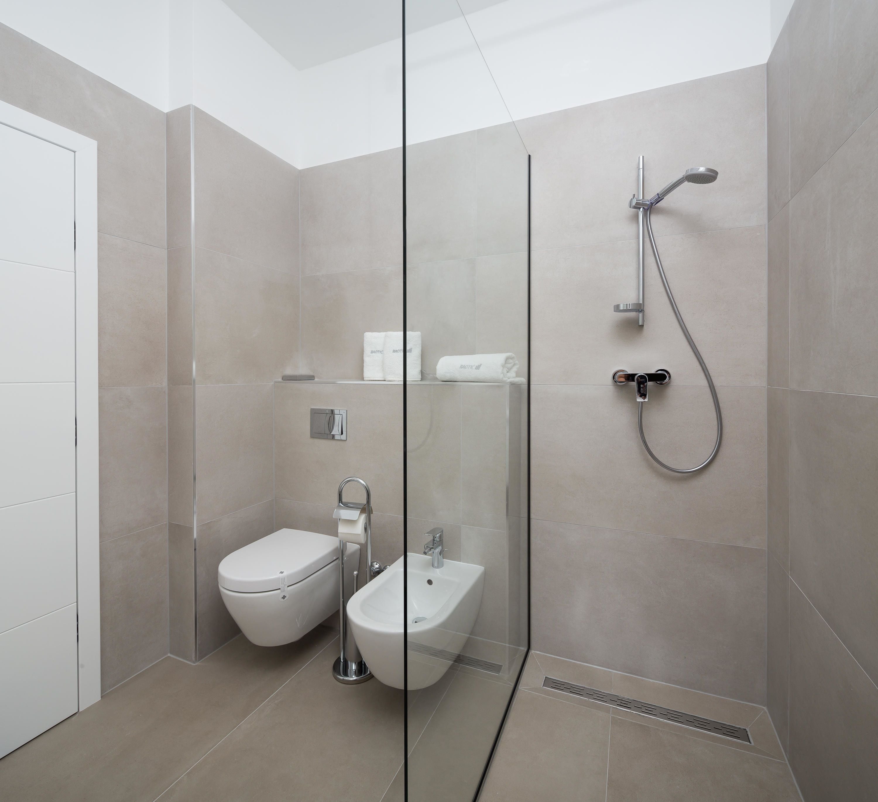 A modern bathroom with a glass partition, a bidet, a toilet, and a shower.