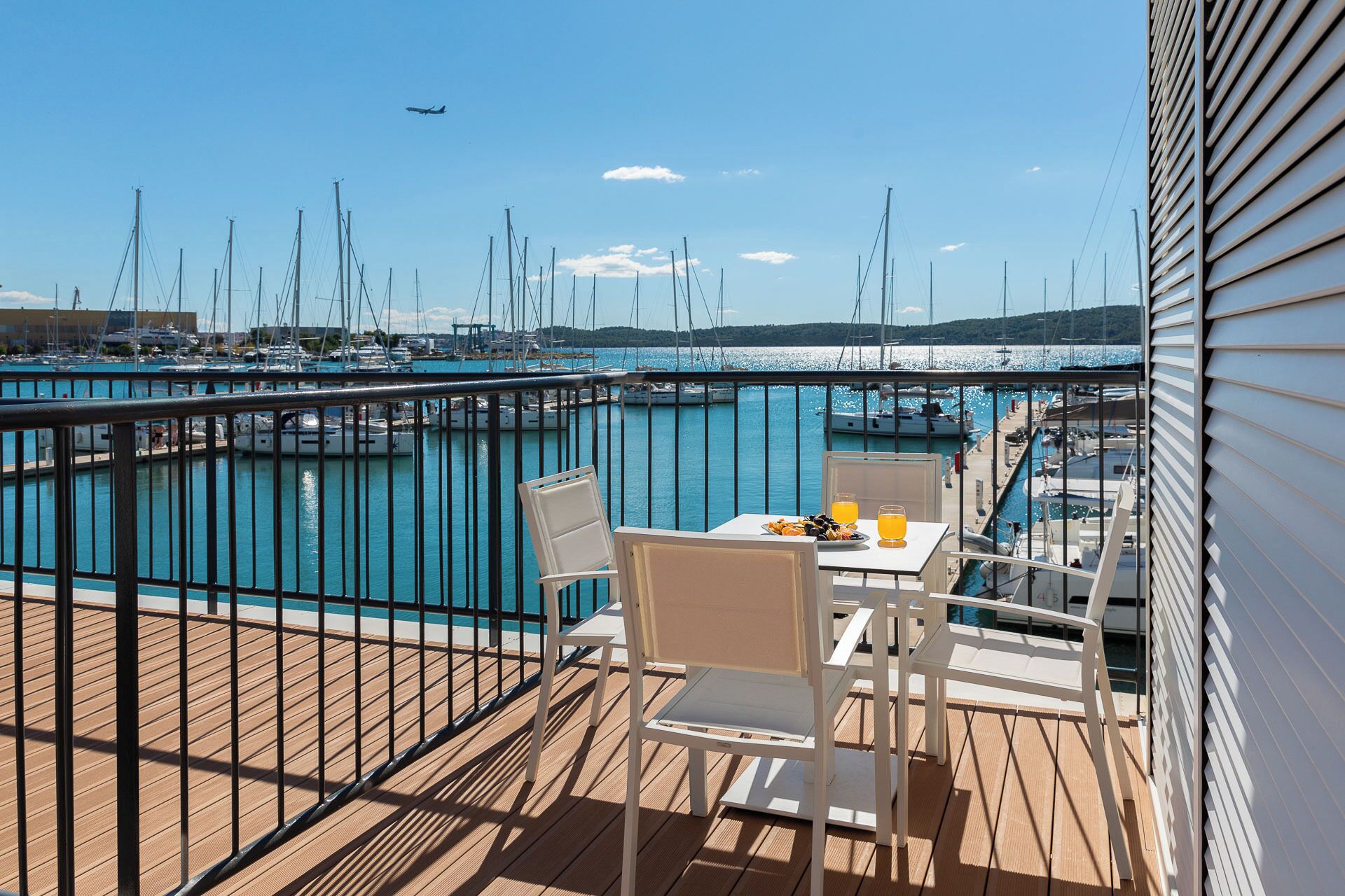 A balcony with a table and chairs overlooking a marina with boats.
