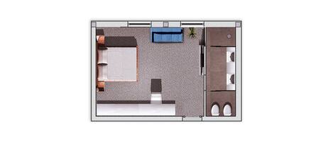 A top-down view of a hotel room with a bed, a small seating area, a kitchenette, and a bathroom.