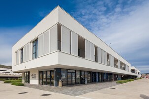 A modern building with a reception area, a covered walkway, and a clear sky.