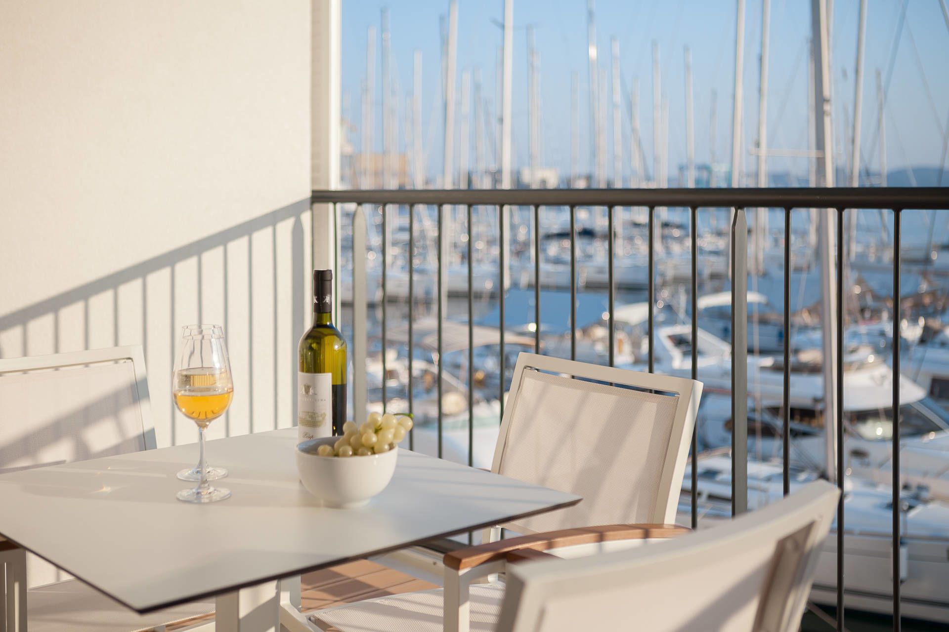 Un balcon avec une table, une bouteille de vin et un verre de vin.