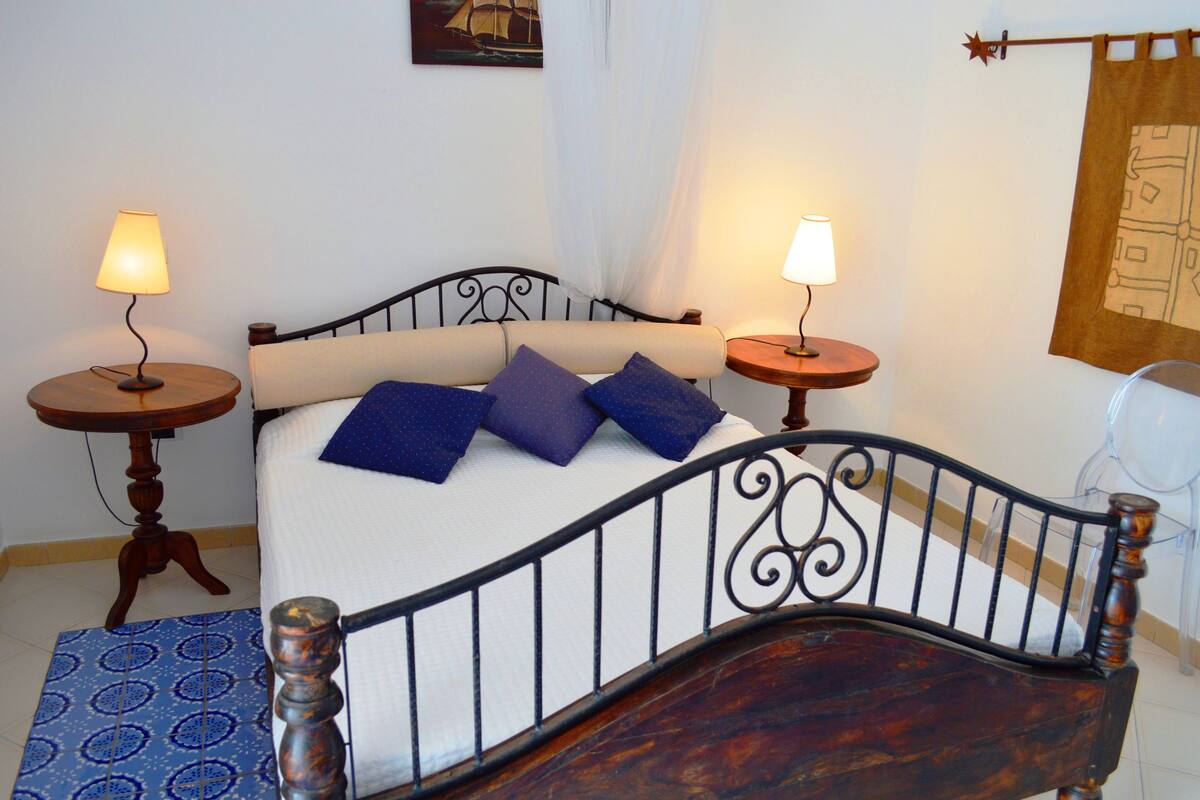 A bed with a wooden headboard, two bedside tables with lamps, and a patterned rug.