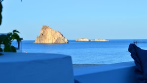 Vista costera con una gran formación rocosa y pequeñas islas a lo lejos.