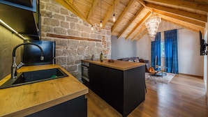 A modern kitchen with a stone wall, wooden beams, and a central island.