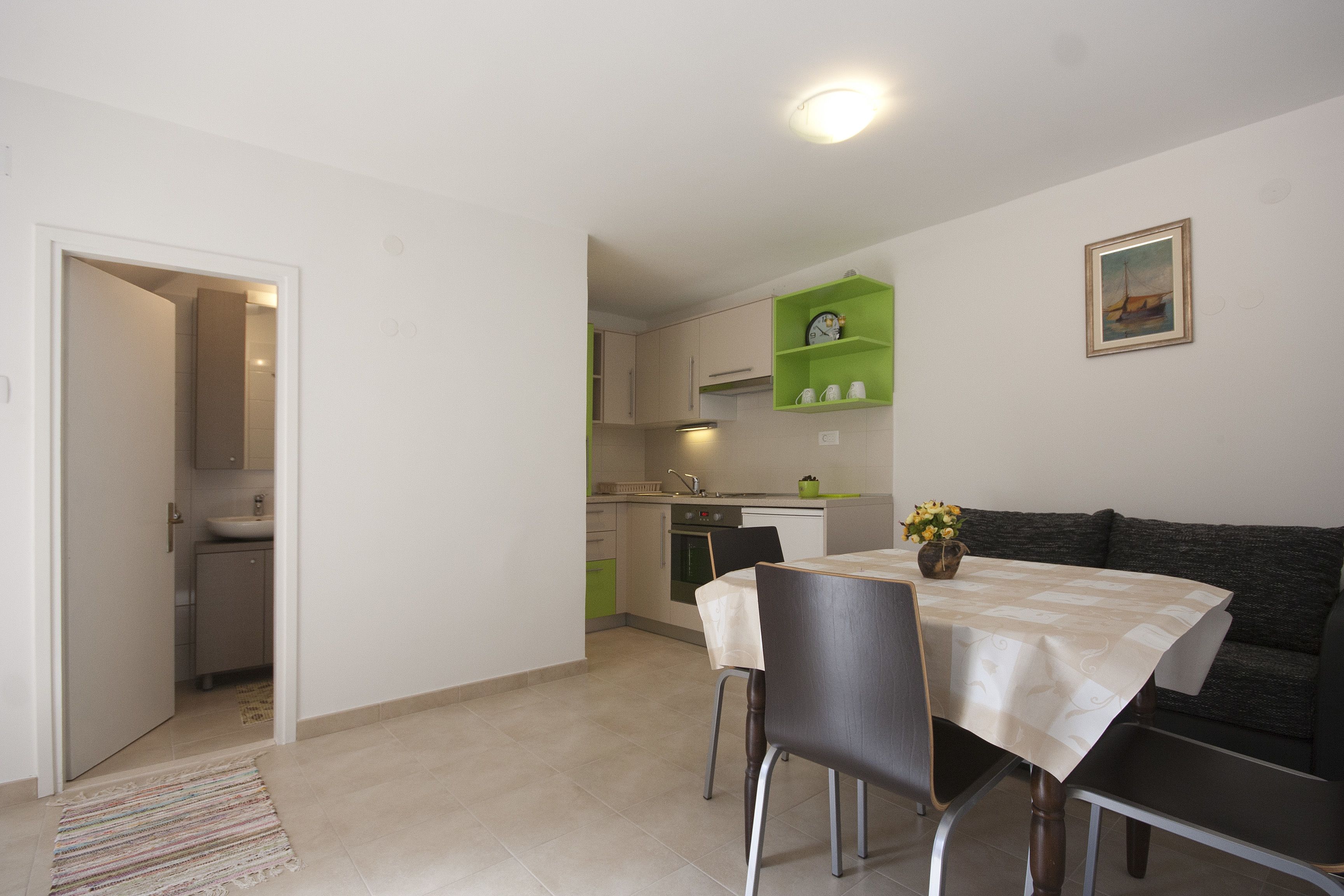 A compact kitchen with a dining area, a sofa, and a small table with chairs.