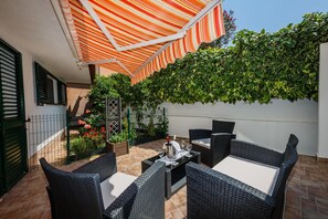 An outdoor patio with wicker furniture, a striped awning, and a wall of greenery. - Villa Spaladium (Split)