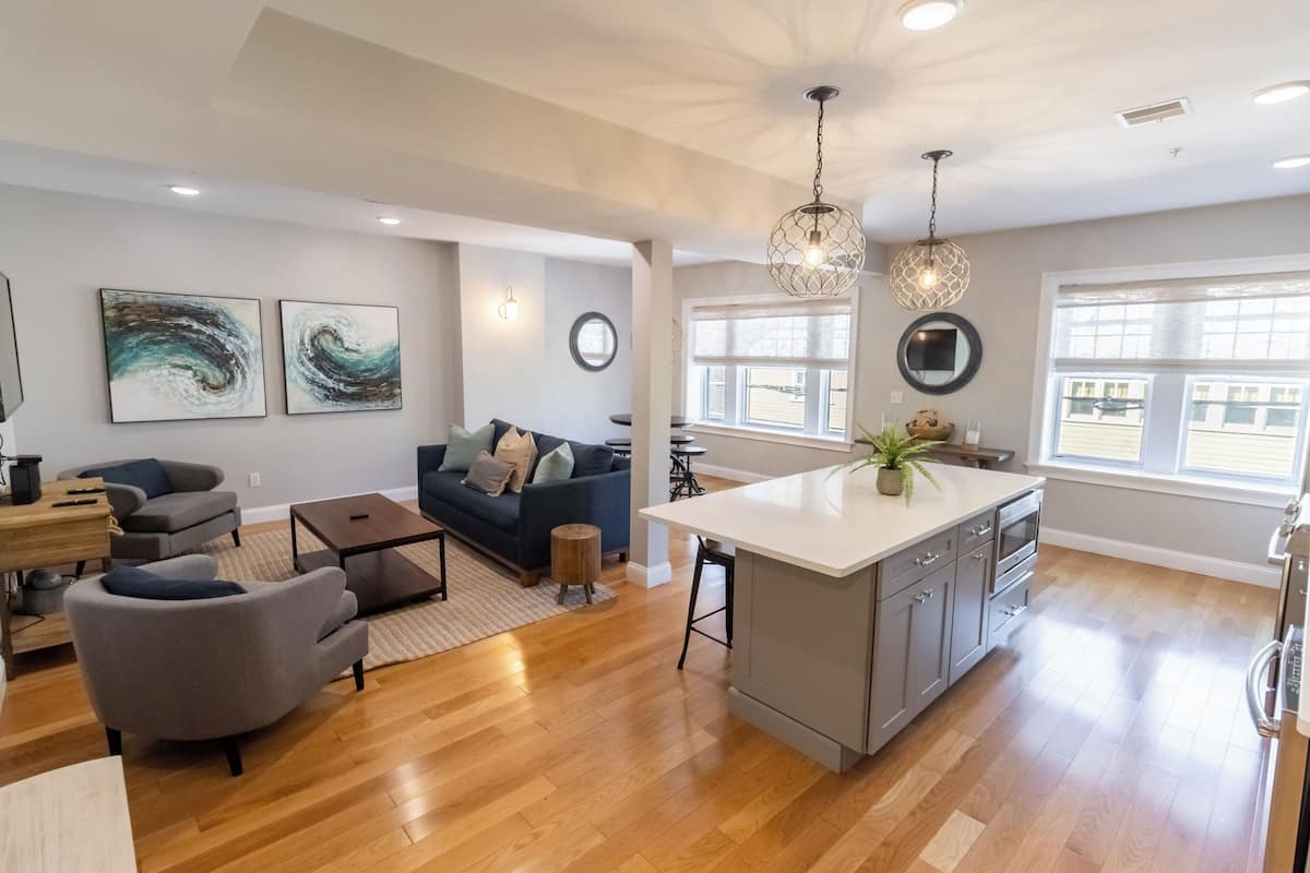 A spacious living area with a gray sofa, a coffee table, and a kitchen island with a sink and cabinets.