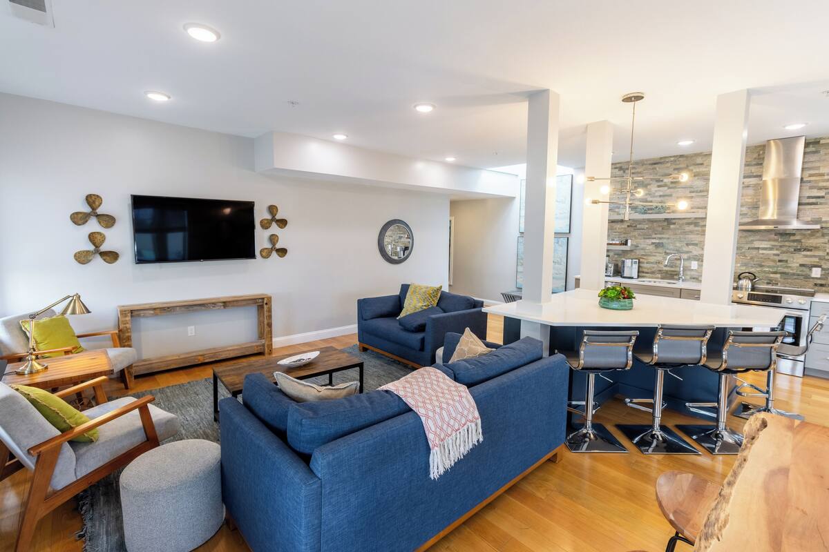 A modern living room with a blue sofa, a wooden coffee table, and a TV mounted on the wall.