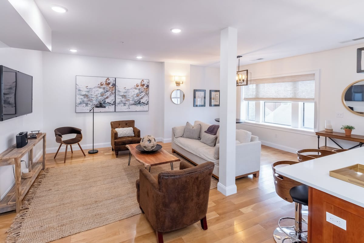 A modern living room with a sofa, armchairs, a coffee table, and artwork on the walls.