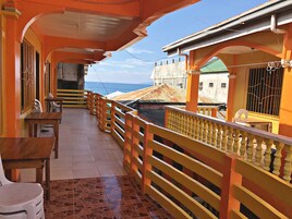 A balcony with a tiled floor, wooden furniture, and a yellow railing.